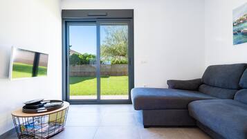 Ein modernes Wohnzimmer mit einem grauen Sofa, einem Couchtisch und einer Schiebeglastür, die in einen Garten führt.