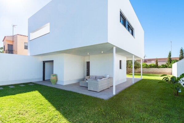 A modern house with a covered patio, a large vase, and a sofa.