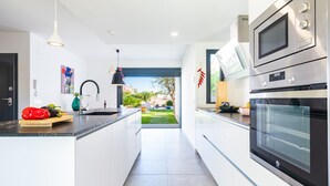 A modern kitchen with a central island, stainless steel appliances, and a view to the outdoors. - Villa Puerto Blanco close to the Beach with Pool & Wi-Fi (Vinaròs)