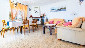 Un comedor con mesa y sillas, un sofá, una chimenea y una pared con un cuadro.