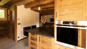 A kitchen with wooden cabinetry, a built-in oven, and a black countertop.