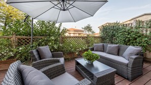 An outdoor patio with wicker furniture, a table, and a large umbrella.