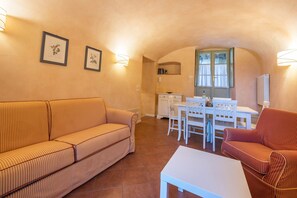 A cozy living area with a sofa, a dining table with chairs, and a kitchen area with a window.