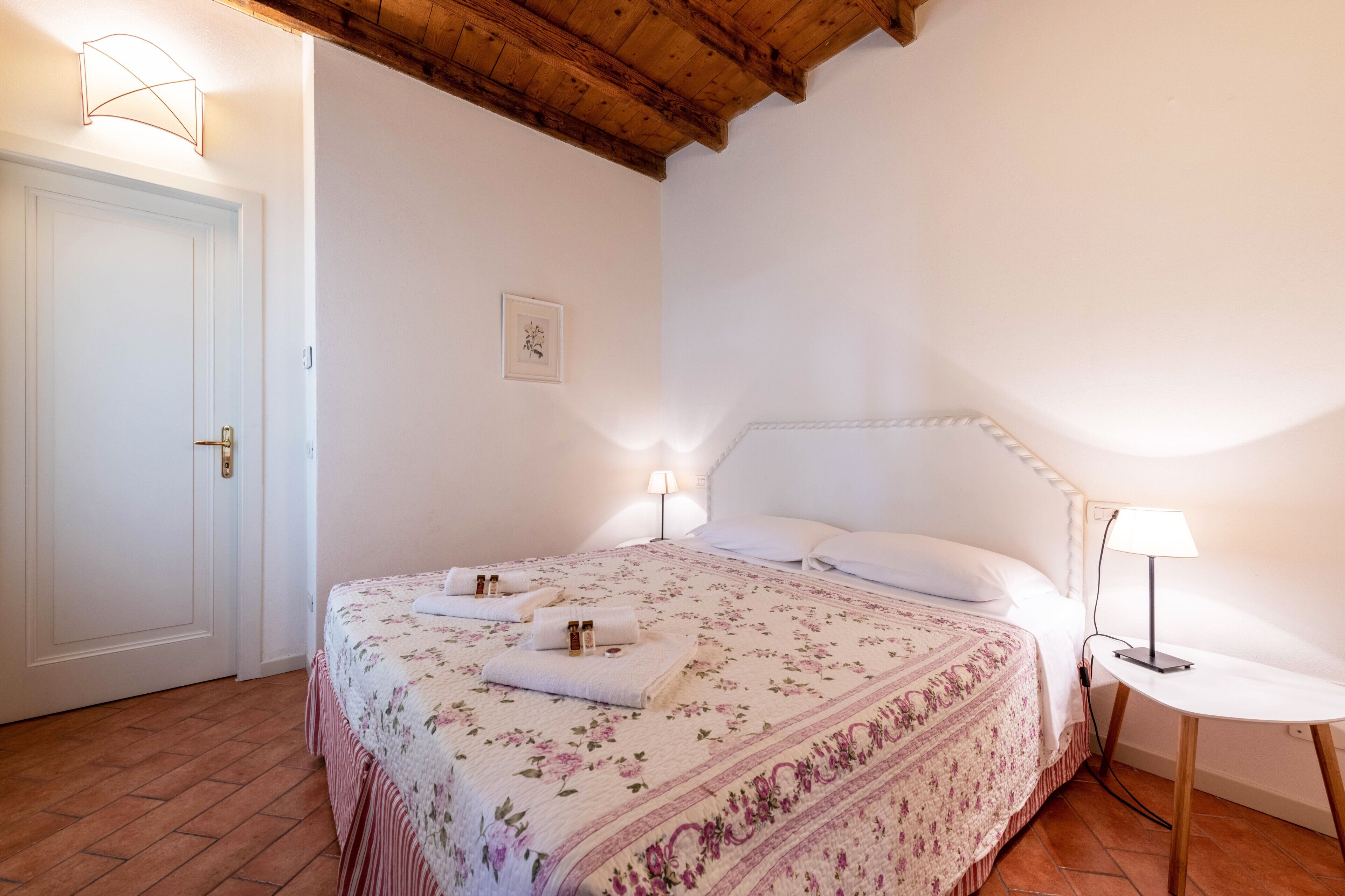 Een slaapkamer met een bed, bedlampen, een deur en een kleine tafel.