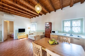 Una cocina con una mesa de madera, un frutero y un microondas.