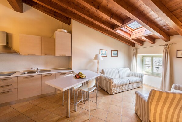 Una cocina con una mesa de comedor, un sofá y un ventanal con cortinas.