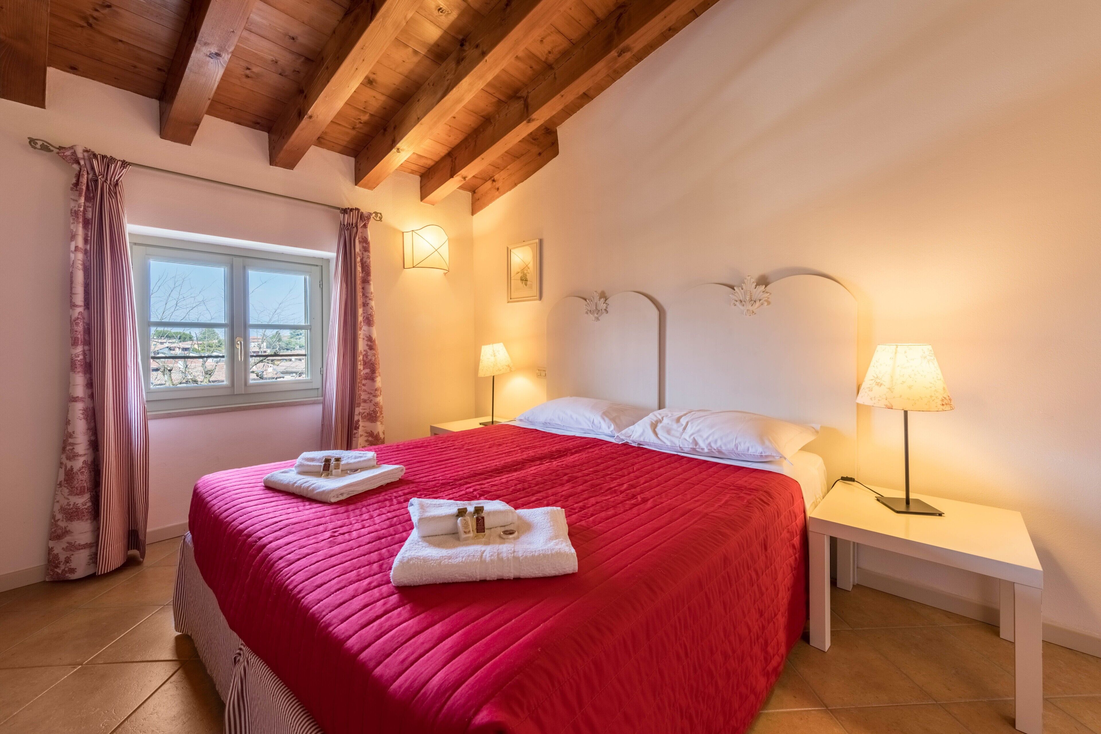 Une chambre d’hôtel avec un lit, deux lampes de chevet, une fenêtre avec des rideaux et une vue sur l’extérieur.