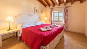 Une chambre à coucher avec un lit, des lampes de chevet, une fenêtre avec des rideaux et un plafond en bois.