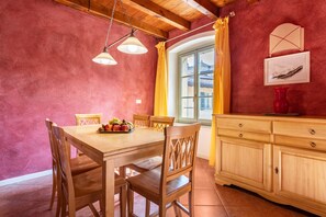 A dining area with a wooden table and chairs, a fruit bowl, and a wooden cabinet with drawers.