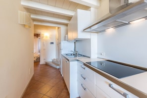 A modern kitchen with white cabinetry, a stainless steel sink, and a built-in stove.