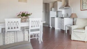 A room with a wooden ceiling, white furniture, a kitchen area, and a tiled floor. - Apartment 'Antica Torre Byron' with Shared Pool, Wi-Fi and Air Conditioning (San Felice del Benaco (BS))