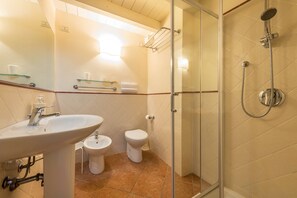 Een badkamer met een wastafel, toilet, bidet en een douchecabine met glazen wanden.