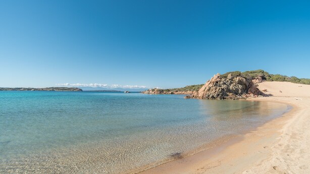 A beach with clear water, sandy shore, and rocky outcrops. - Apartment 'Rifla Vacanze' with Terrace & Wi-Fi (La Maddalena)