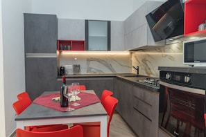 Une cuisine moderne avec un coin repas, un four encastré et un four à micro-ondes.
