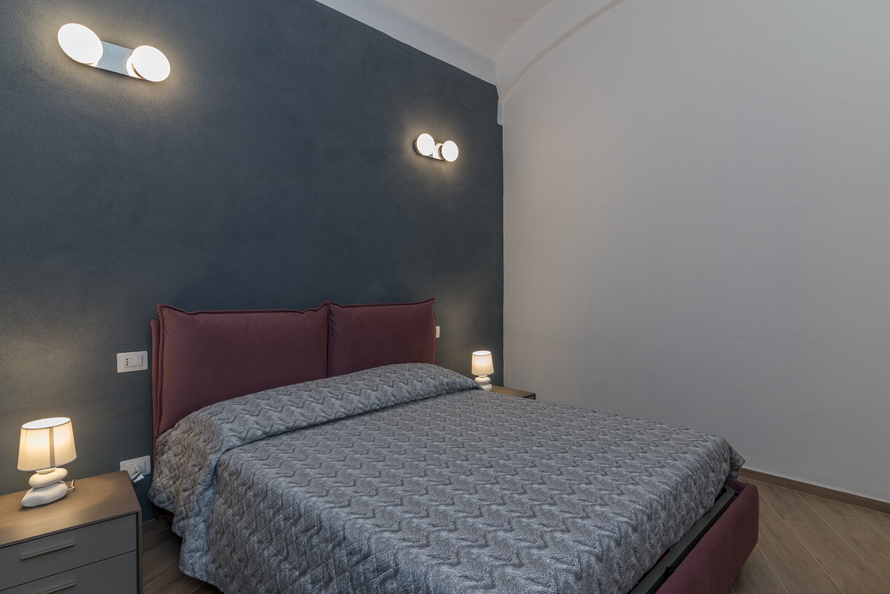 Une chambre à coucher avec un lit, des tables de chevet et des lampes fixées au mur.