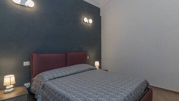 Une chambre à coucher avec un lit, des tables de chevet et des lampes fixées au mur.