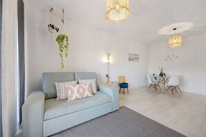 Un salon moderne avec un canapé, une table à manger et des chaises, ainsi que des plantes suspendues.