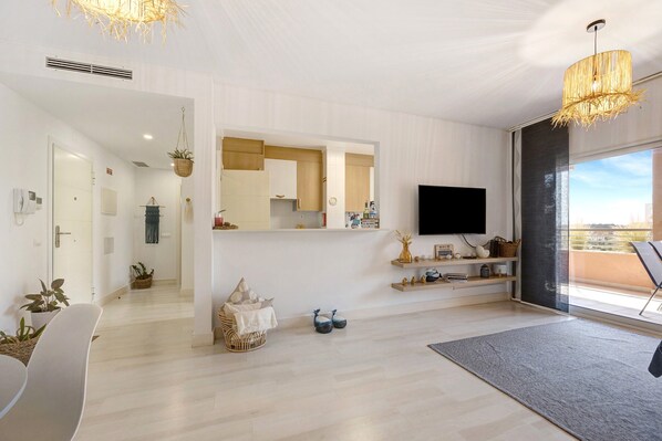 Un soggiorno moderno con una TV a schermo piatto, un grande specchio e un'area pranzo con sedie e tavolo.