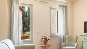 Een kamer met een bank, een stoel, een bijzettafeltje met een vaas en een kast.