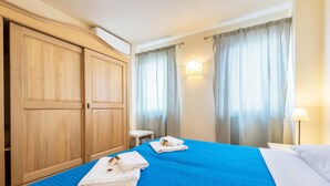 Een hotelkamer met een groot bed, een houten garderobe, een klein tafeltje en een lamp.