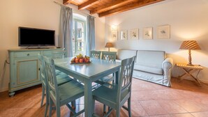 A dining area with a table, chairs, a television, and a sofa.