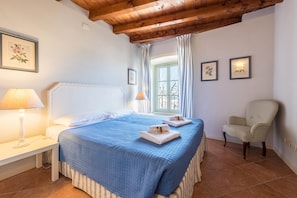 A bedroom with a bed, bedside tables, a chair, and a window with curtains.