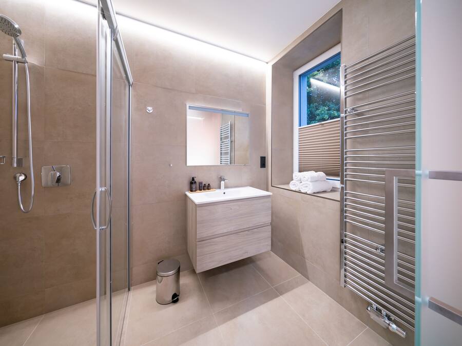 A modern bathroom with a glass shower enclosure, a vanity with a mirror, and a towel rack.