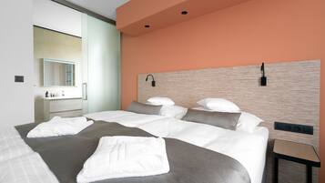 A modern hotel room with a large bed, a bedside table, a built-in shelf, and a mirror.