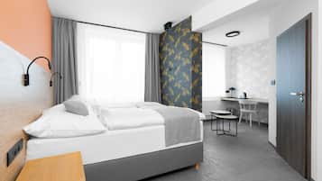 Une chambre d’hôtel moderne équipée d’un lit, d’une table de chevet, d’un bureau et d’une chaise.