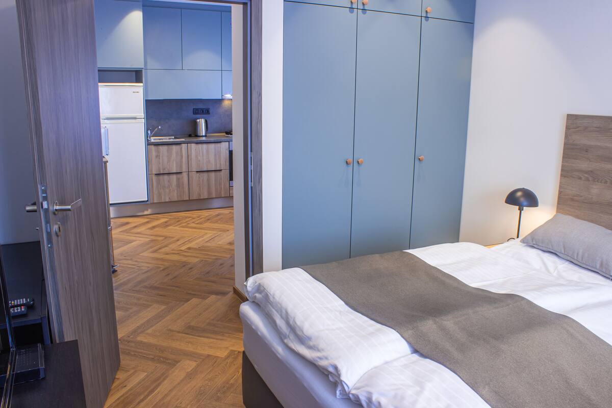 A bedroom with a bed, a bedside table, a lamp, and a wardrobe.