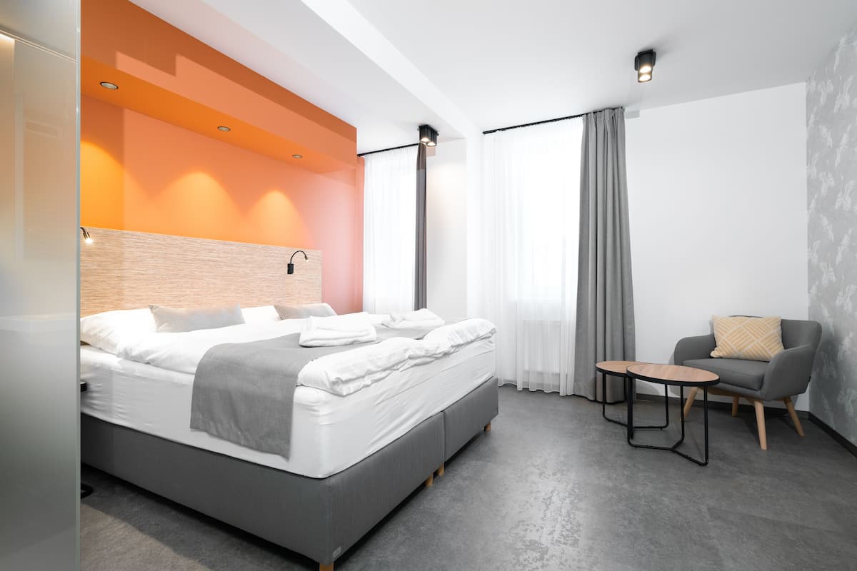 A modern hotel room with a large bed, a small table, and a chair.