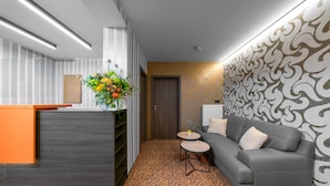 Un área de recepción de diseño moderno, con mostrador de recepción, un sofá gris y un papel tapiz con diseño.