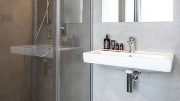 A modern bathroom with a glass-enclosed shower, a white sink, and a mirror above it.