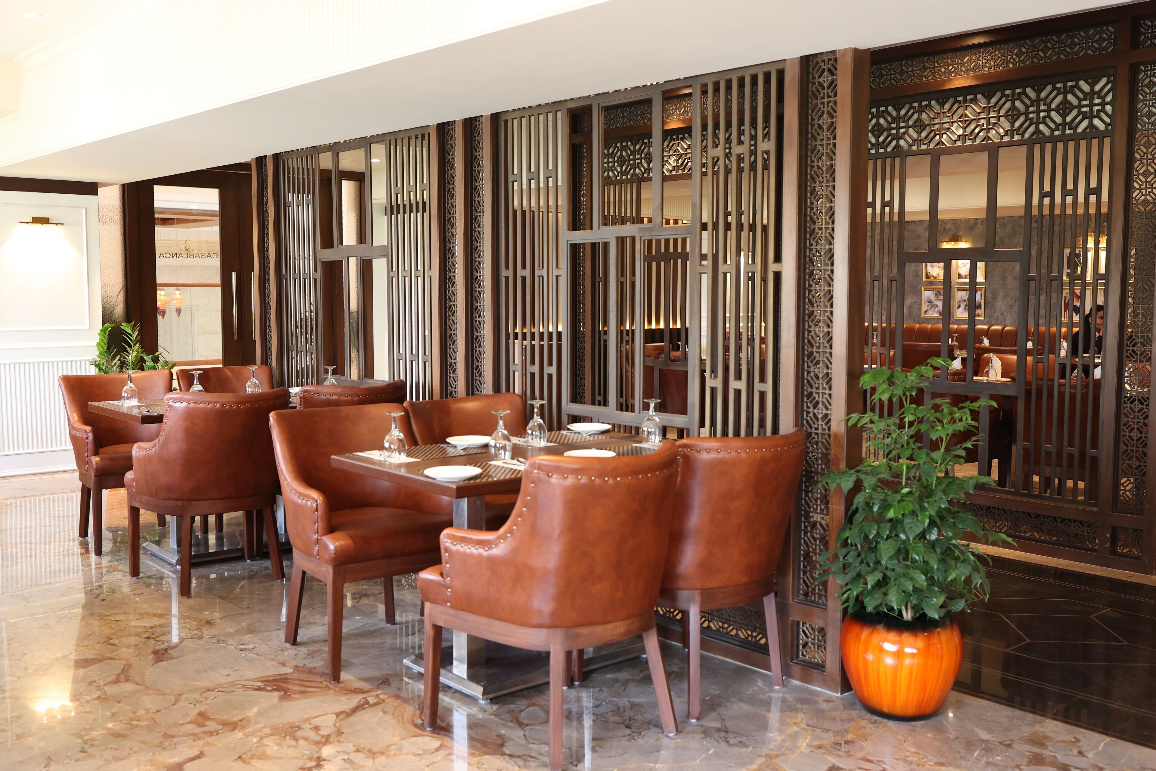 A restaurant with wooden furniture and a large potted plant.