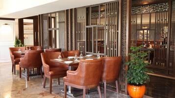 A restaurant with wooden furniture and a large potted plant.