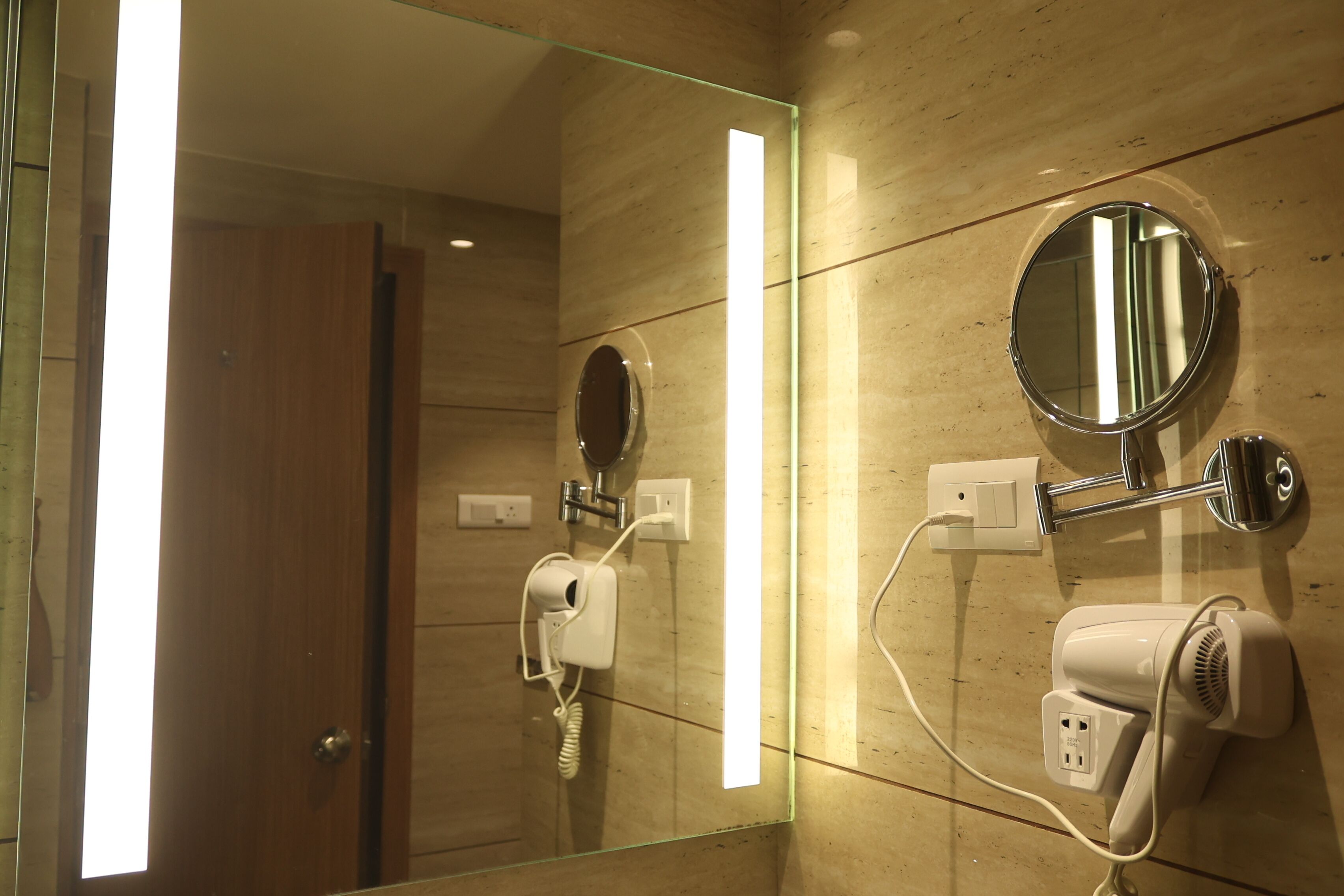 A bathroom with a glass partition, a mirror, a hairdryer, and a towel warmer.