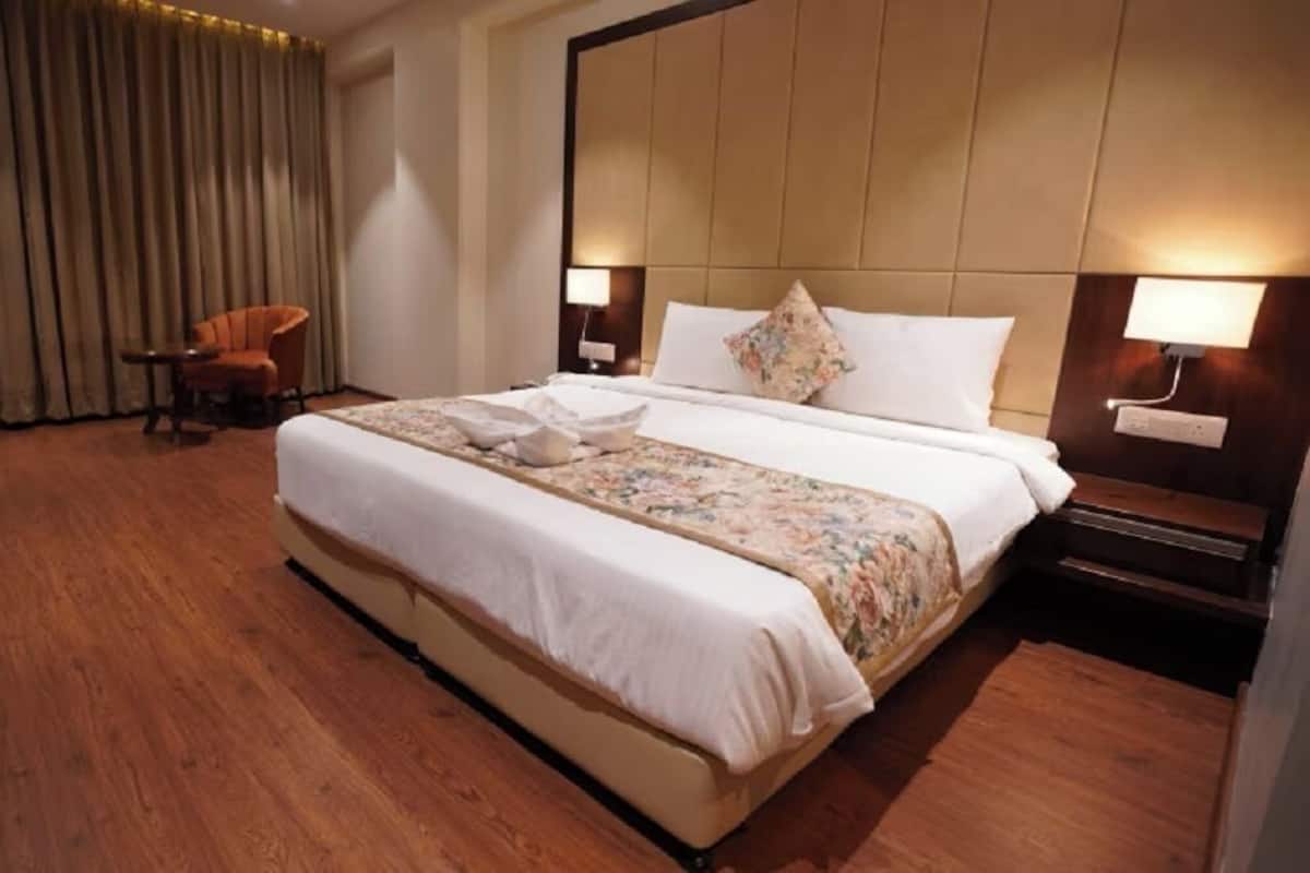 Una habitación de hotel con una cama grande, una silla, un escritorio y una cortina.