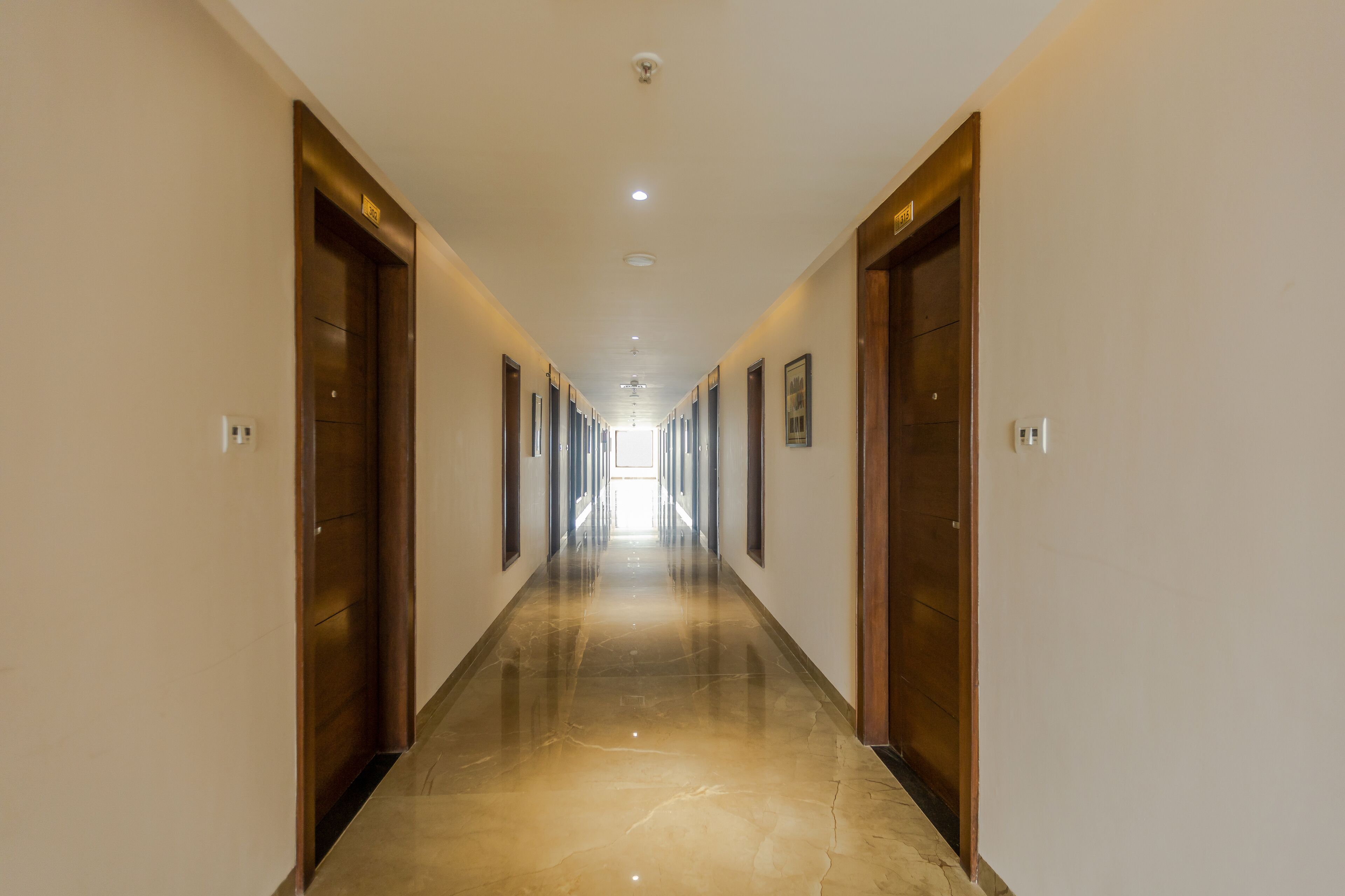 A long, narrow hallway with wooden doors on either side and a shiny, reflective floor.