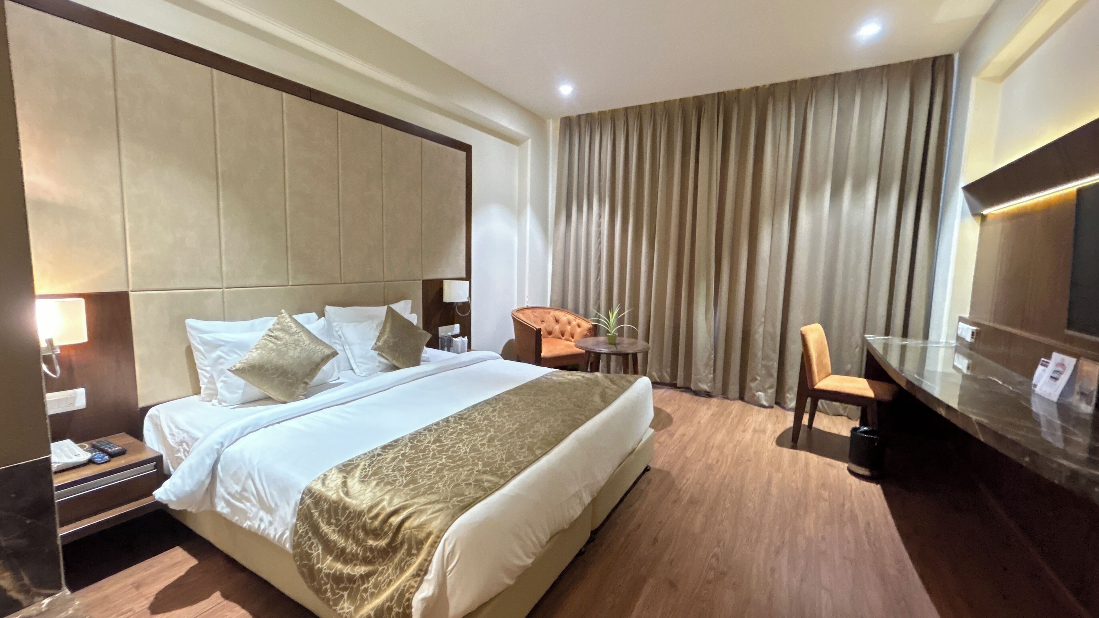 A hotel room with a large bed, a desk, a chair, and a television.