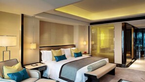 Ein modernes Hotelzimmer mit einem großen Bett, Nachttischen, einem Schreibtisch und einer Sitzecke.