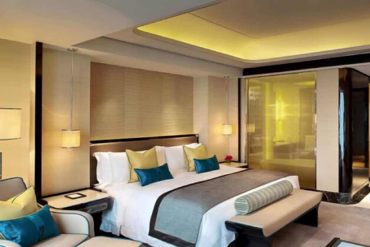 Una habitación de hotel moderna con una cama grande, mesitas de noche, un escritorio y una zona de estar.