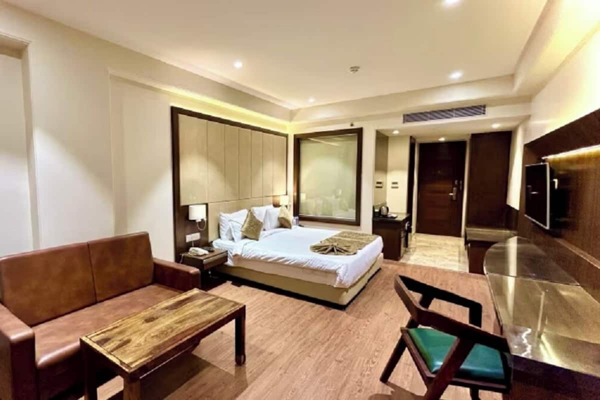 Habitación de hotel con cama, sofá, mesa de centro, televisor y escritorio.