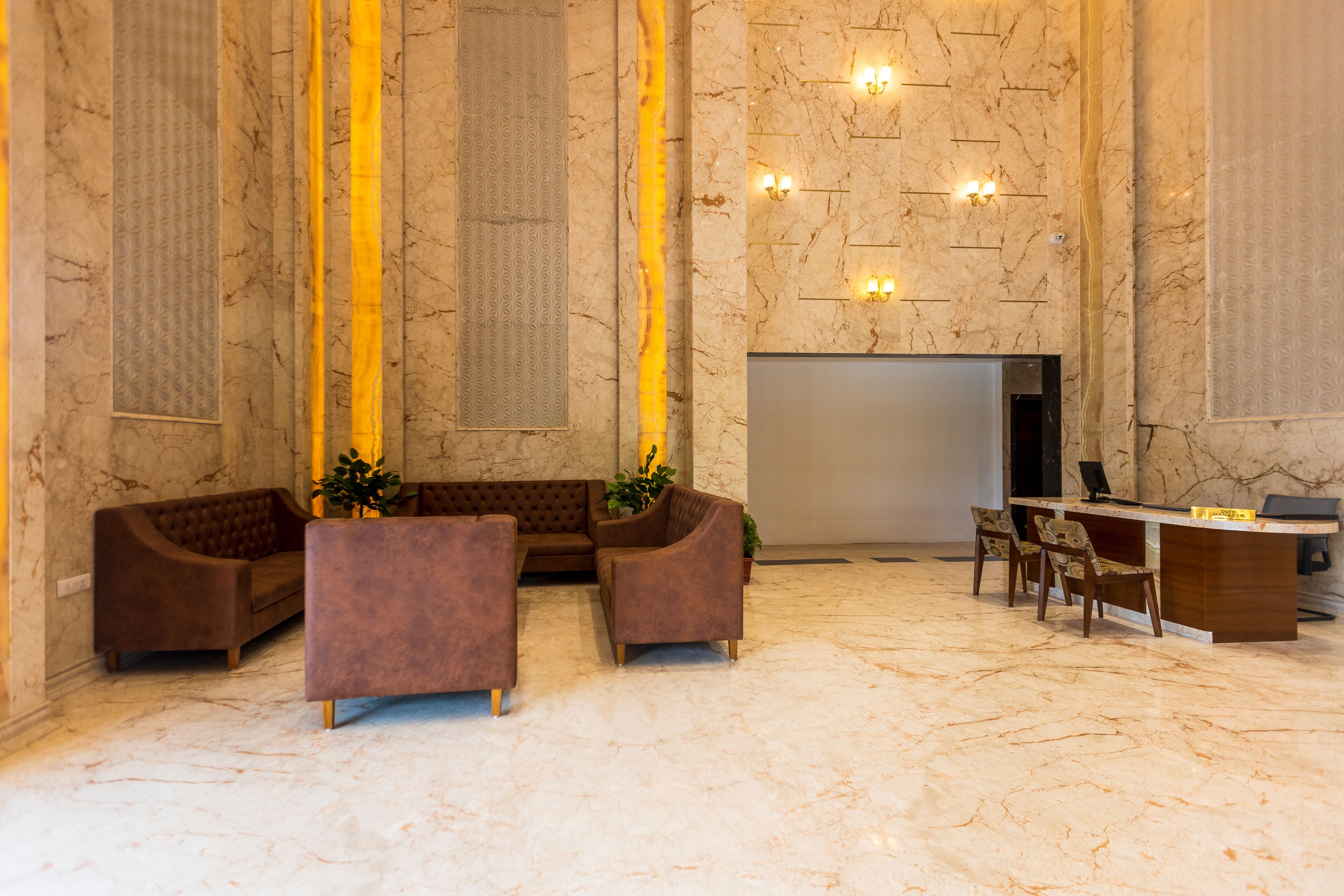 A lobby with a reception desk, seating area, and marble flooring.