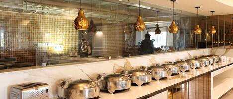 A buffet setup with multiple food containers and a toaster on a marble countertop.