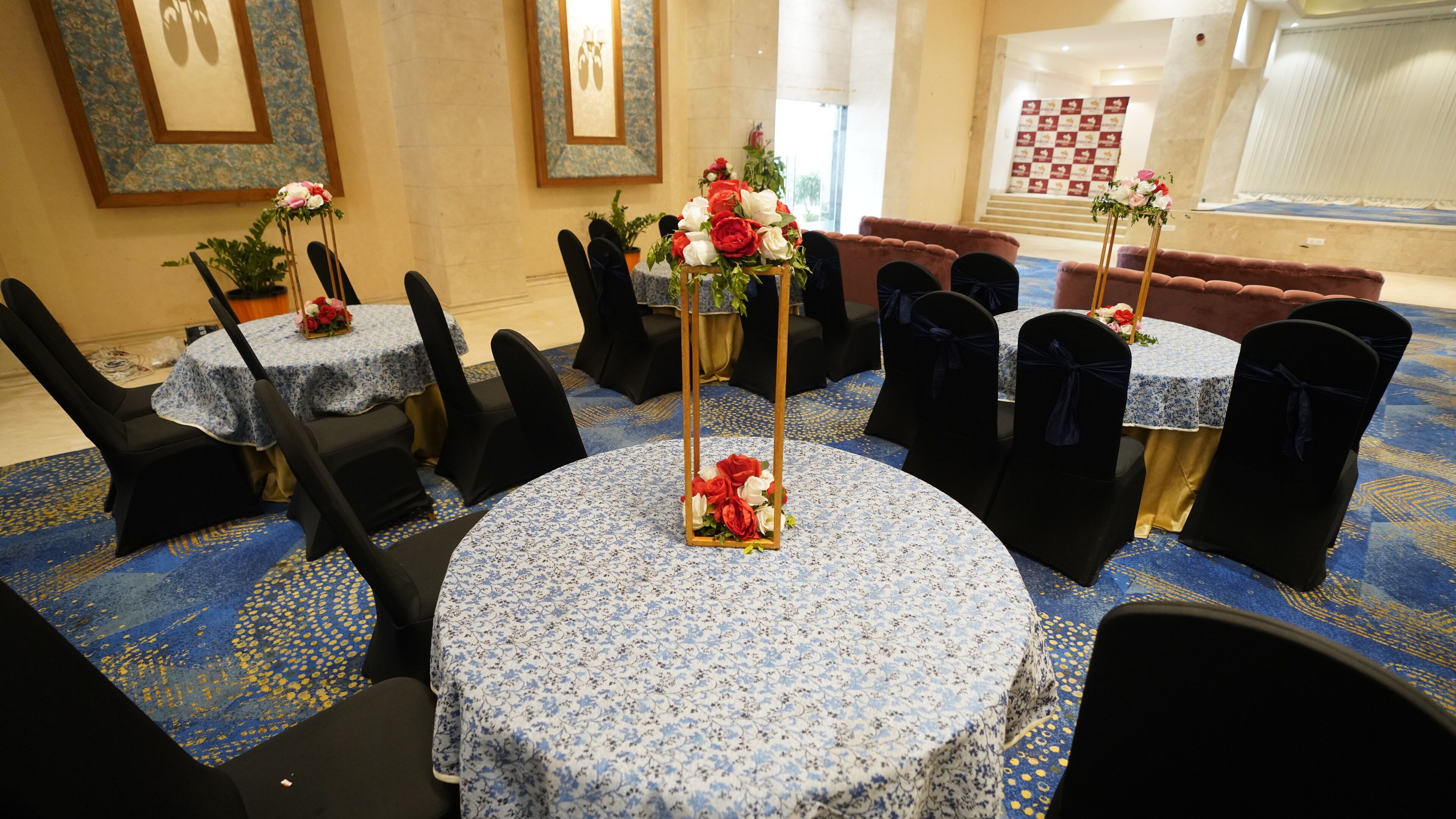 A conference room with round tables, black chairs, and floral centerpieces.