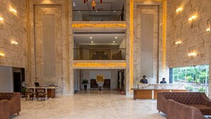 Eine geräumige Lobby mit Marmorböden, einem Empfangsbereich, Sitzgelegenheiten und Blick ins Freie.