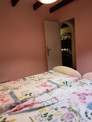A bedroom with a bed covered in floral bedding, a white headboard, and a pink wall. - Vacation home with a beautiful ocean view (La Croix-Valmer)