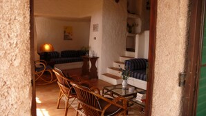 Ein gemütliches Wohnzimmer mit einer Couch, Sesseln, einem Couchtisch und einer Treppe, die in eine obere Etage führt.