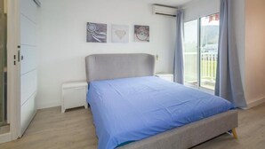 Ein Schlafzimmer mit einem Bett, einem Nachttisch, einem Fenster mit Vorhängen und Wandbildern.