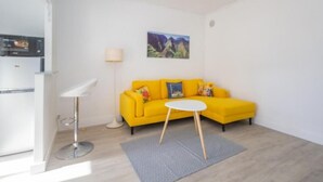 Ein hellgelbes Sofa mit einem kleinen weißen Tisch davor, einer Lampe und einem Gemälde an der Wand.